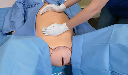 Simulador Noelle com vestimentas de paciente hospitalar prestes a entrar em trabalho de parto
