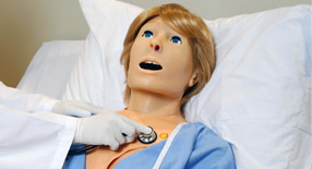 Profissional aferindo pressão arterial de simulador Susie em leito hospitalar