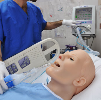 Simulador Hal deitado em leito hospitalar com profissionais da área da saúde