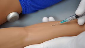 Profissional realizando injeção intravenosa no braço do simulador